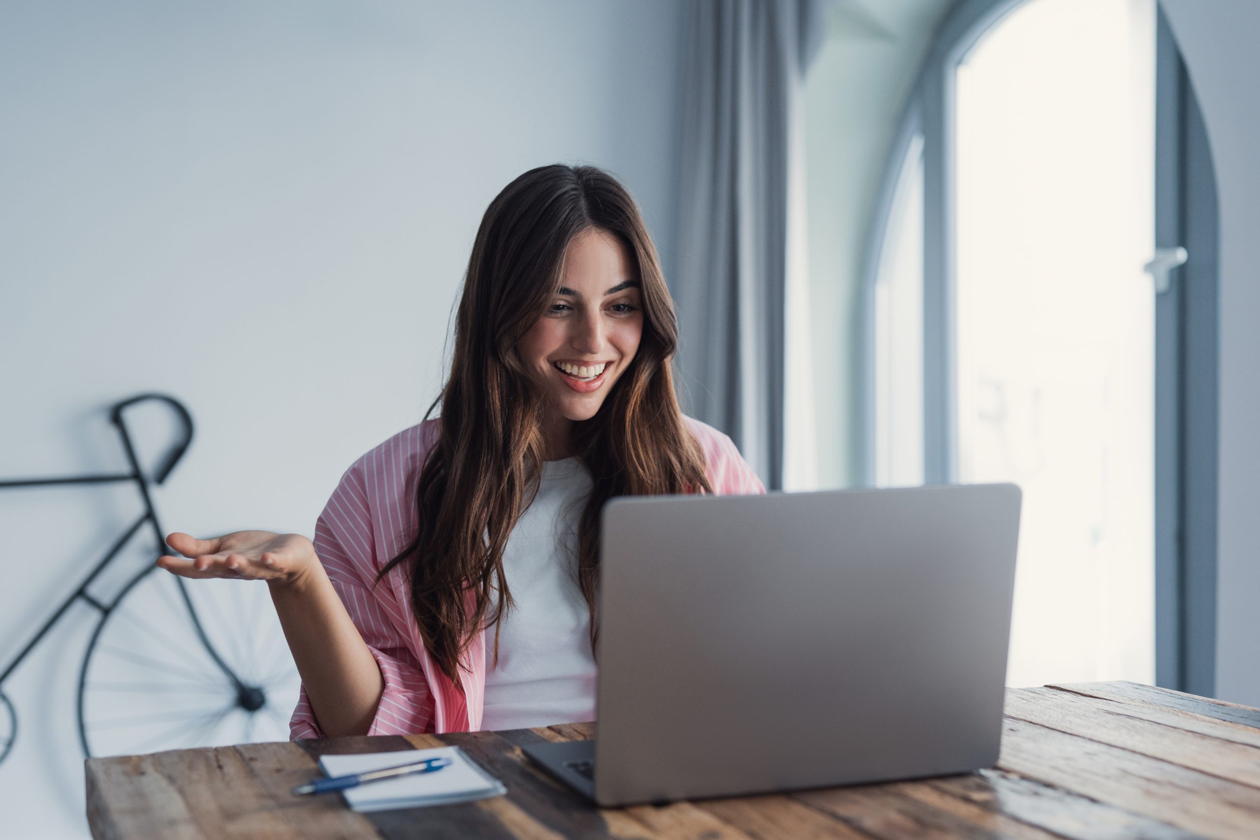 A,Cheerful,Young,Woman,Uses,A,Laptop,For,An,Online